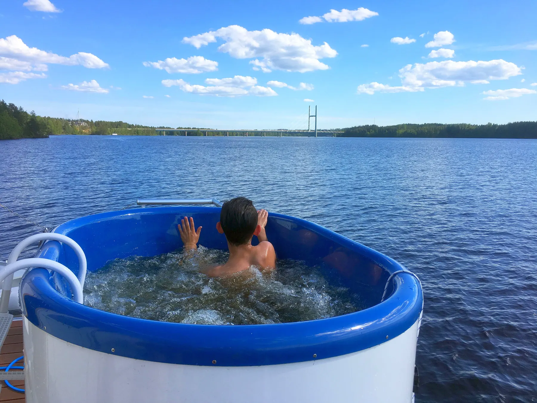 Guest relaxing in a hot tub on a houseboat deck overlooking a lake